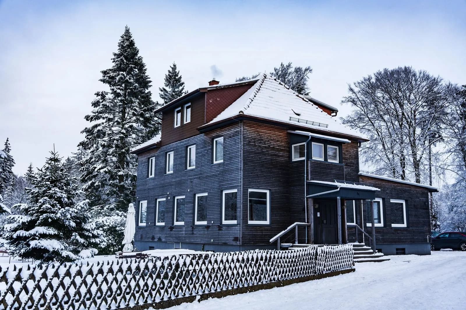Maison québécoise sous la neige avec épinettes
